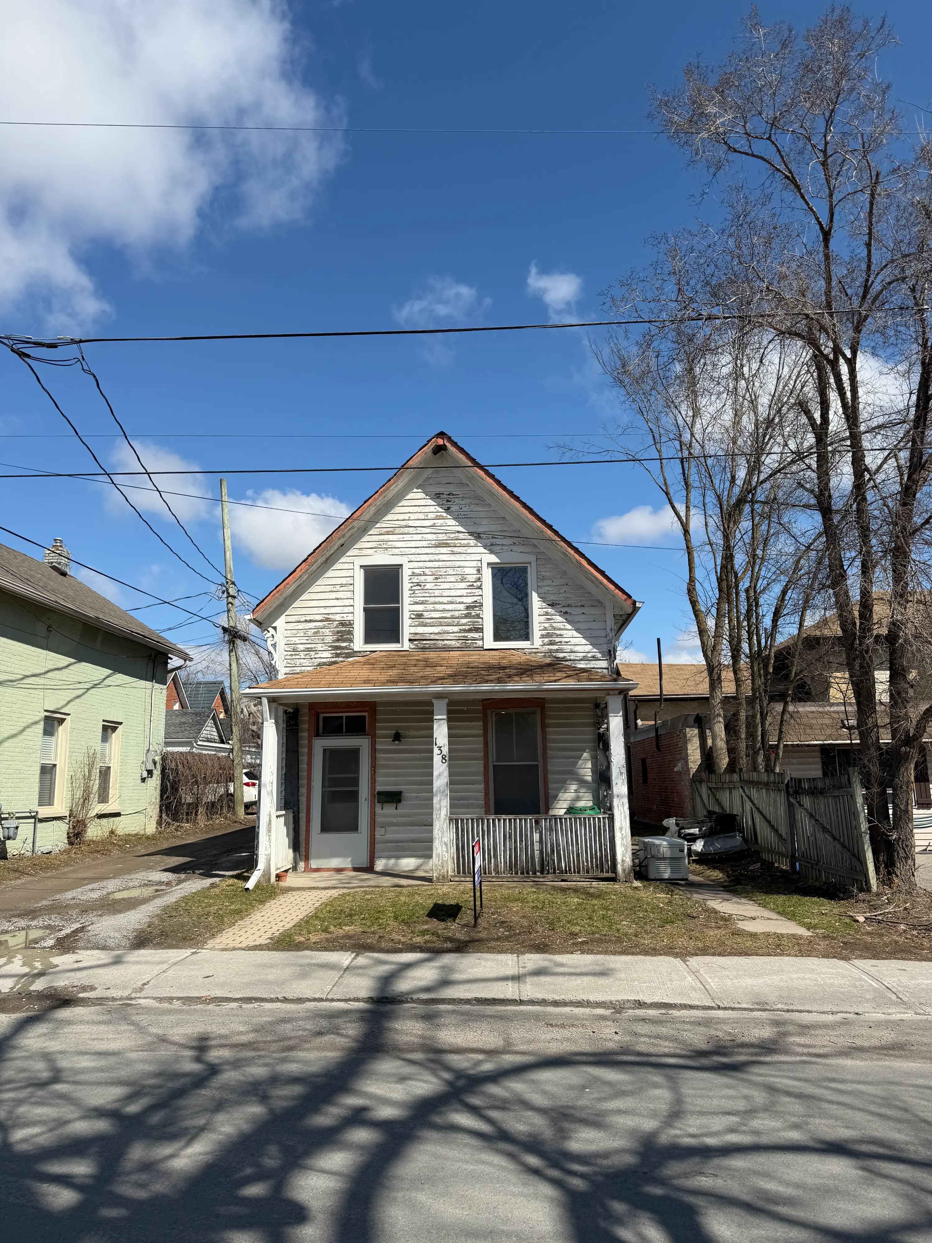 brick two-storey house with a for-sale sign on the front lawn in an Ontario neighbourhood