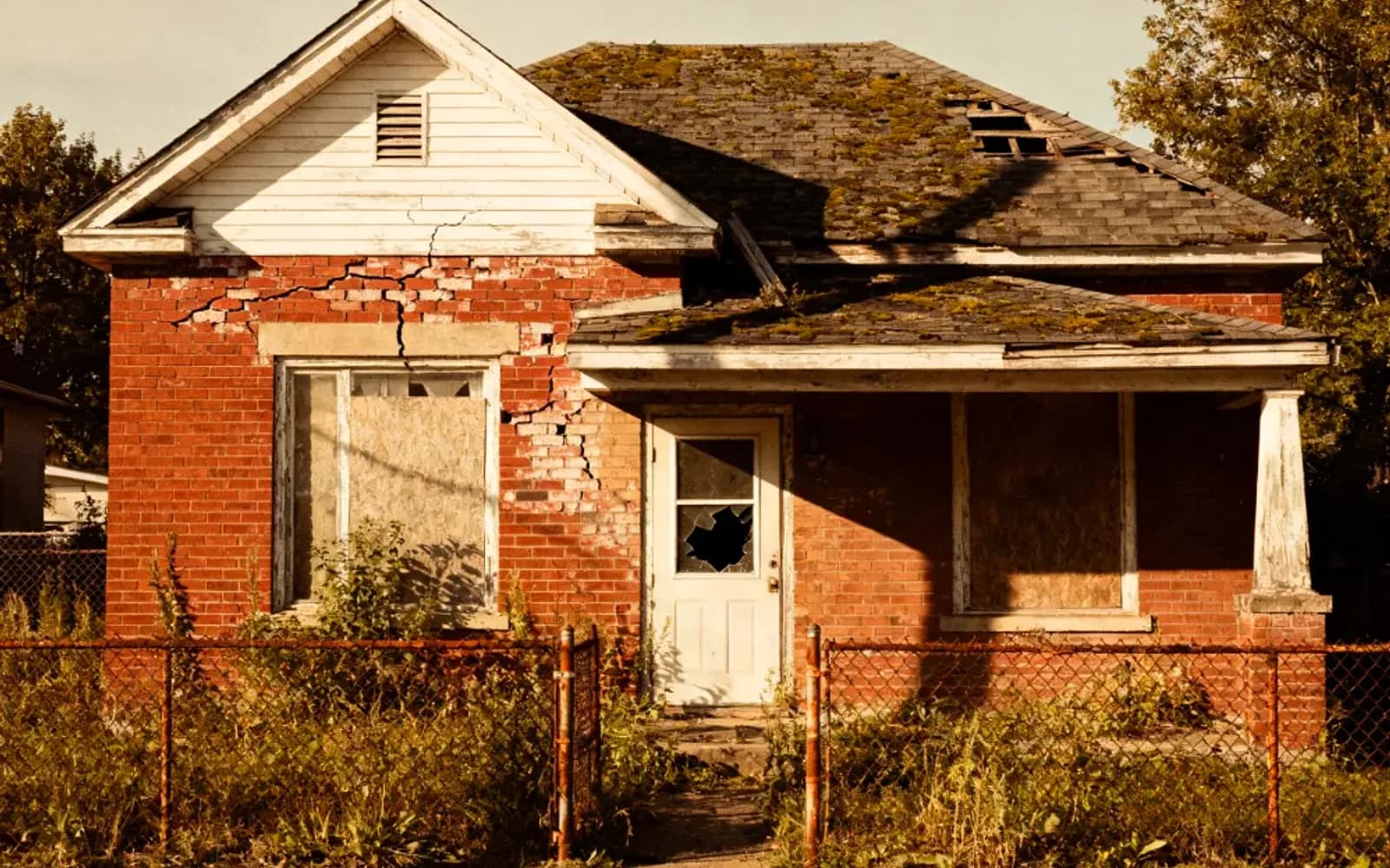 Distressed red-brick bungalow with a cracked wall, sold as-is in Kingston, Ontario