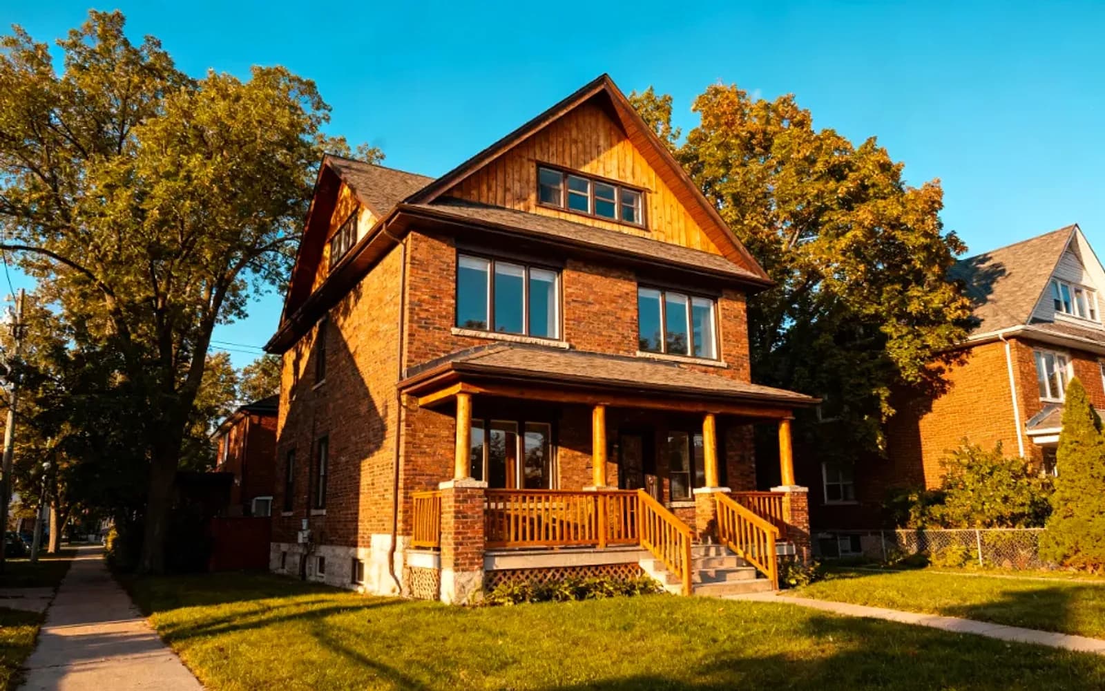 Two-and-a-half-storey brick home with a covered front porch at golden hour in Port Perry, Ontario