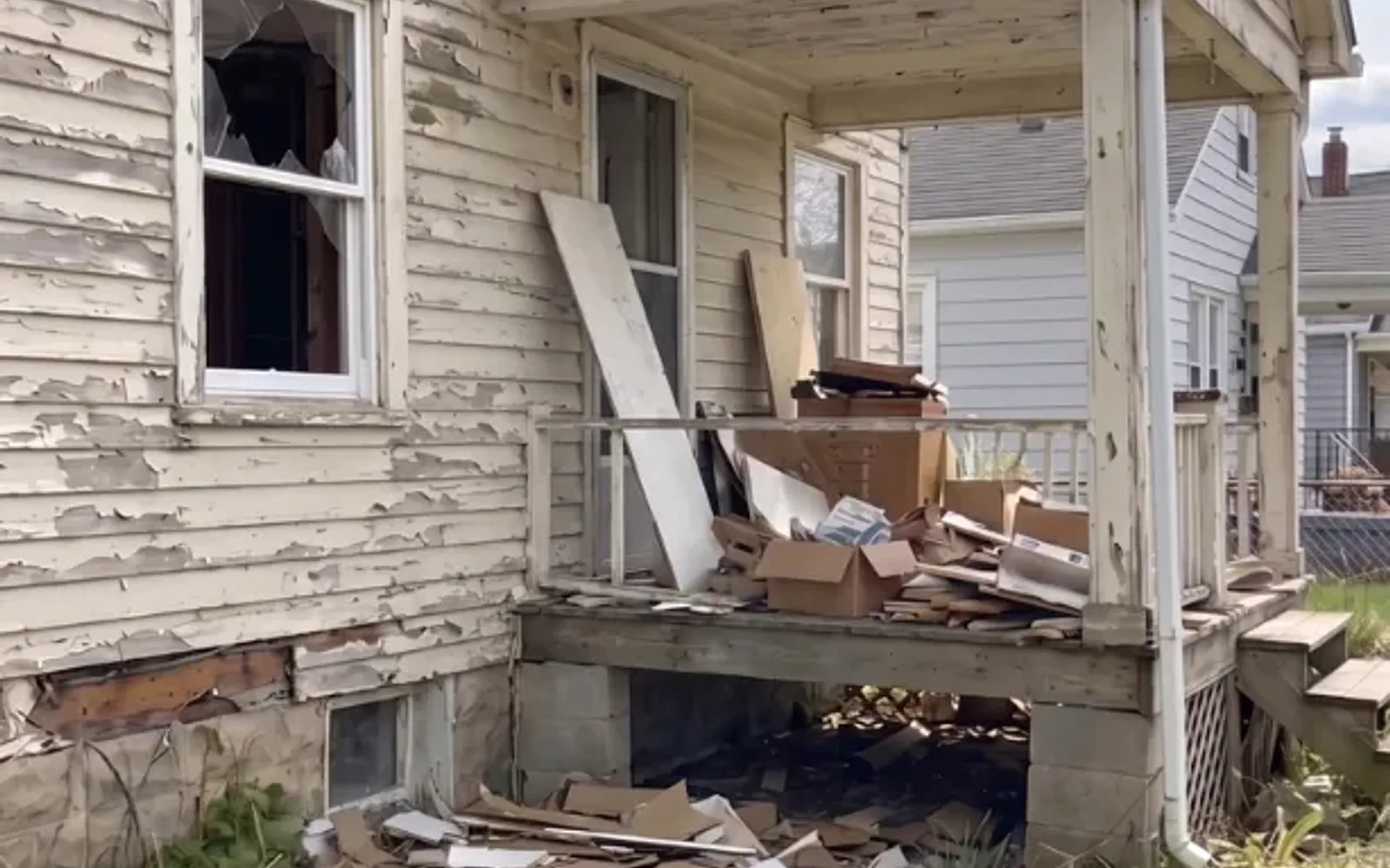 Weathered cream-sided home with peeling paint being sold as-is in St. Catharines, Ontario