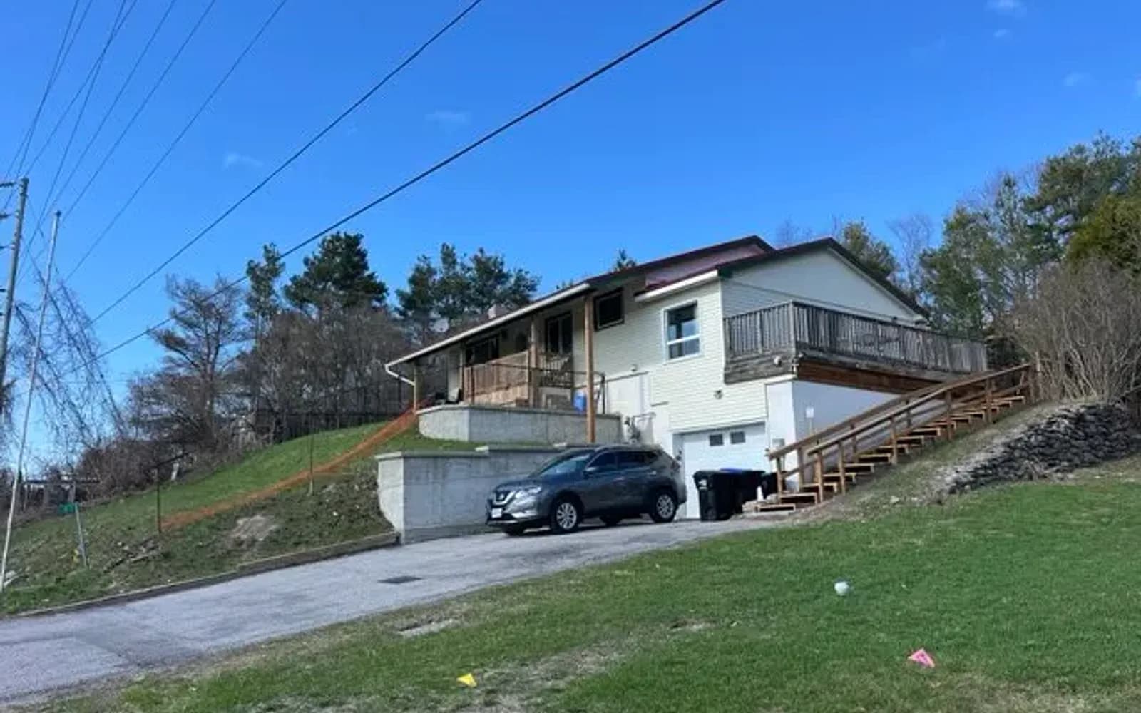 White raised bungalow with a deck on a sloped lot in Cambridge, Ontario