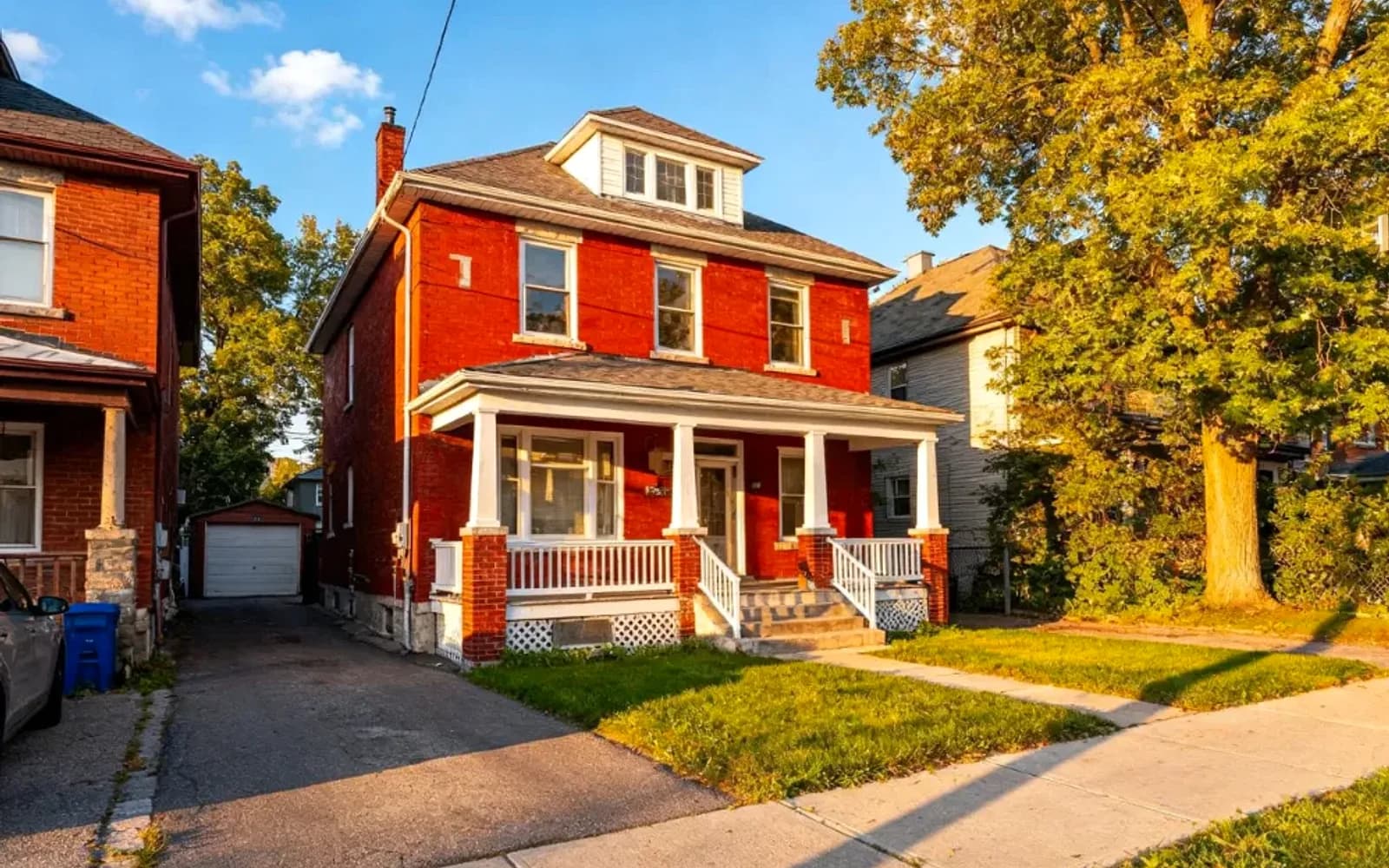 Red-brick two-and-a-half-storey home with a covered porch at golden hour in Clarington, Ontario