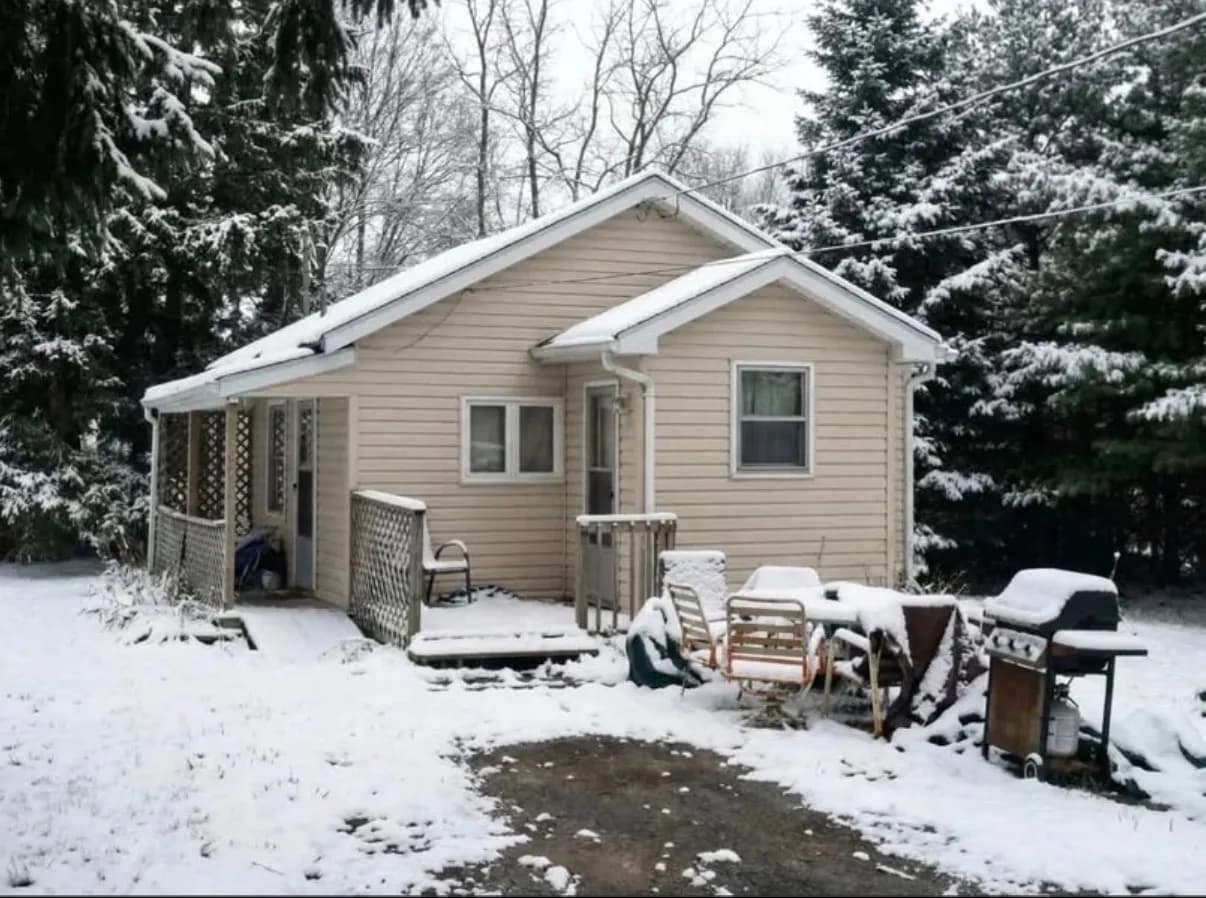 Weathered board-and-batten house with peeling trim being sold as-is in Grimsby, Ontario