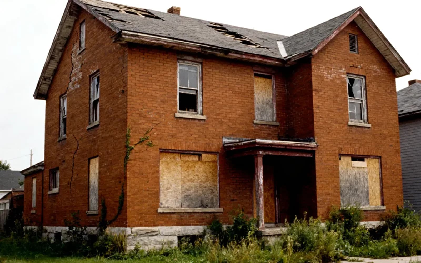 Boarded-up red brick two-storey home bought as-is for cash in Halton Hills, Ontario