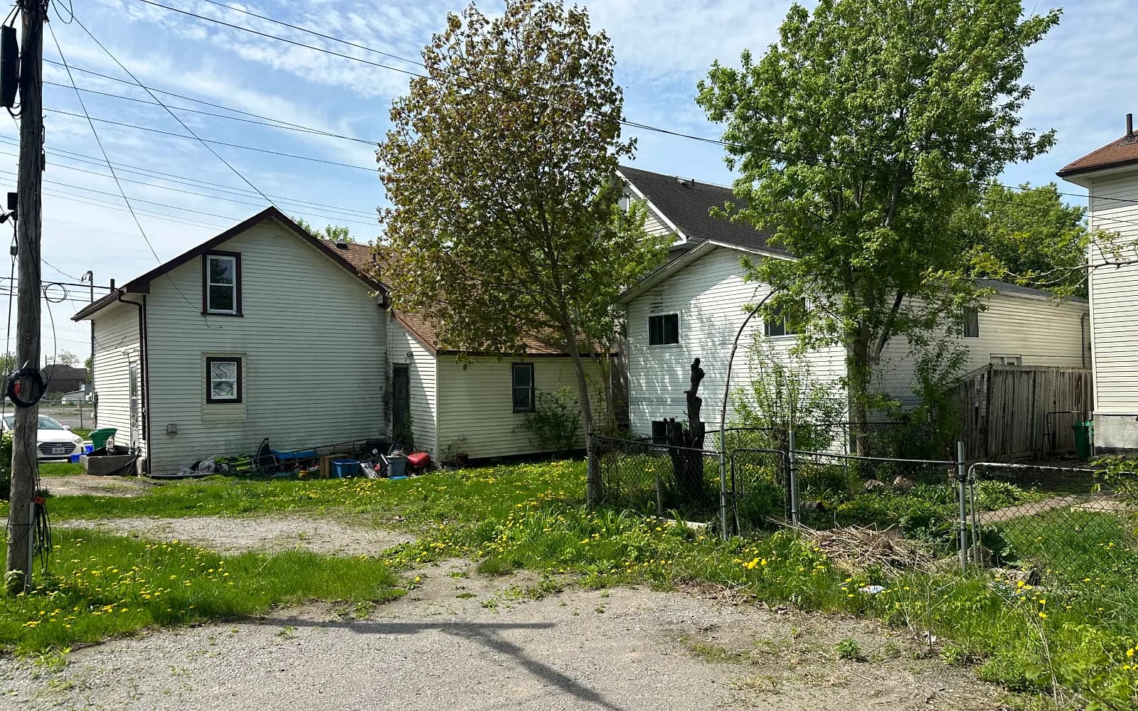Weathered white-sided home with a fenced backyard on a sunny day in Havelock, Ontario
