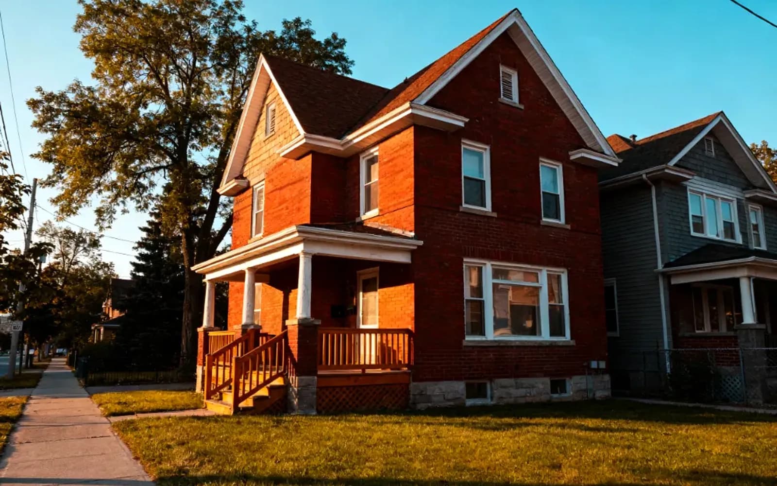 Red-brick Victorian home with a covered porch at golden hour in Niagara Falls, Ontario
