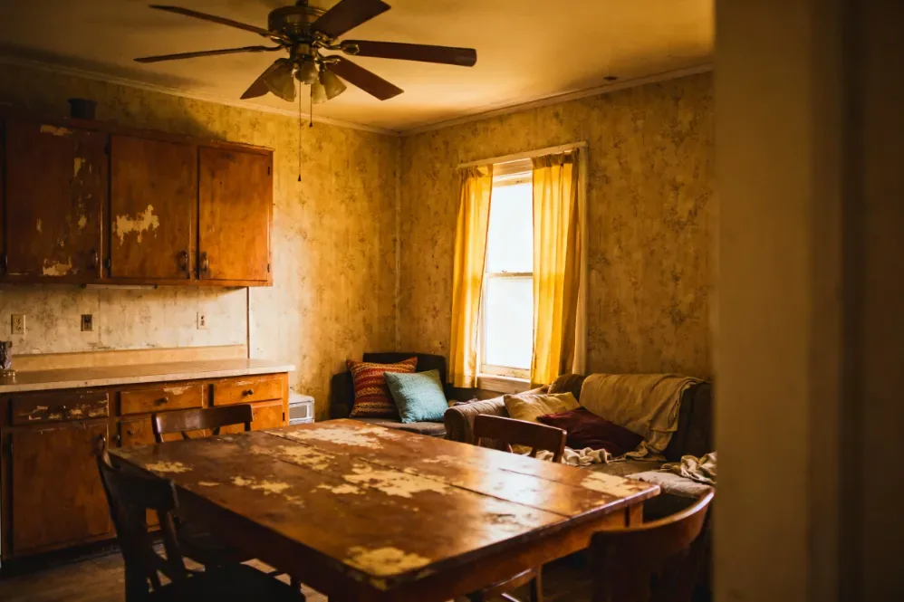 Dated interior of an as-is home for sale in Paris, Ontario, with a worn kitchen and peeling wallpaper