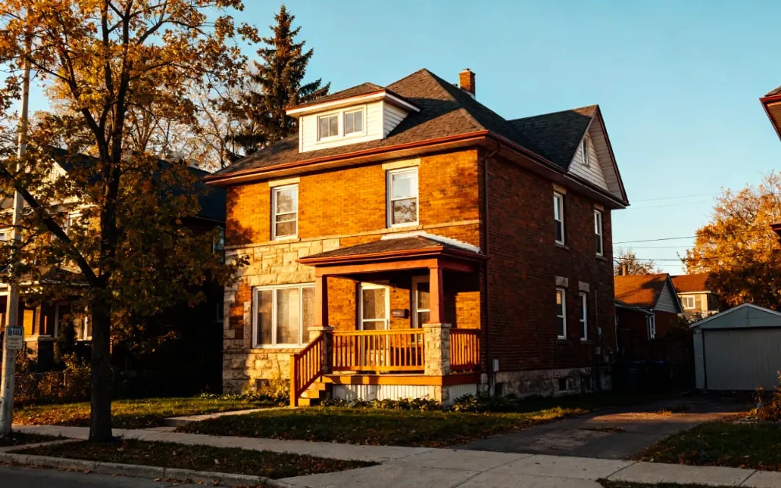 Brick two-and-a-half-storey home with a covered porch at golden hour in Keswick, Ontario
