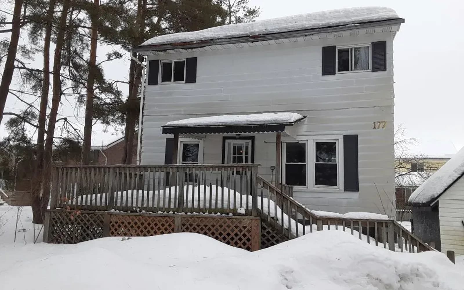 White two-storey home with a wood deck on a snowy lot in Wallaceburg, Ontario