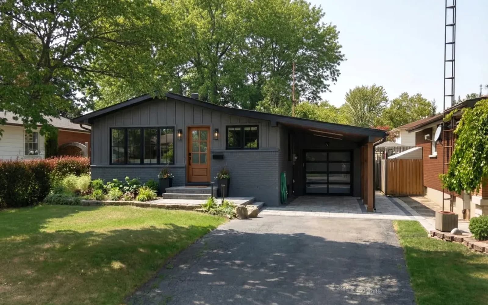 Renovated grey bungalow with an attached garage on a sunny street in Thunder Bay, Ontario