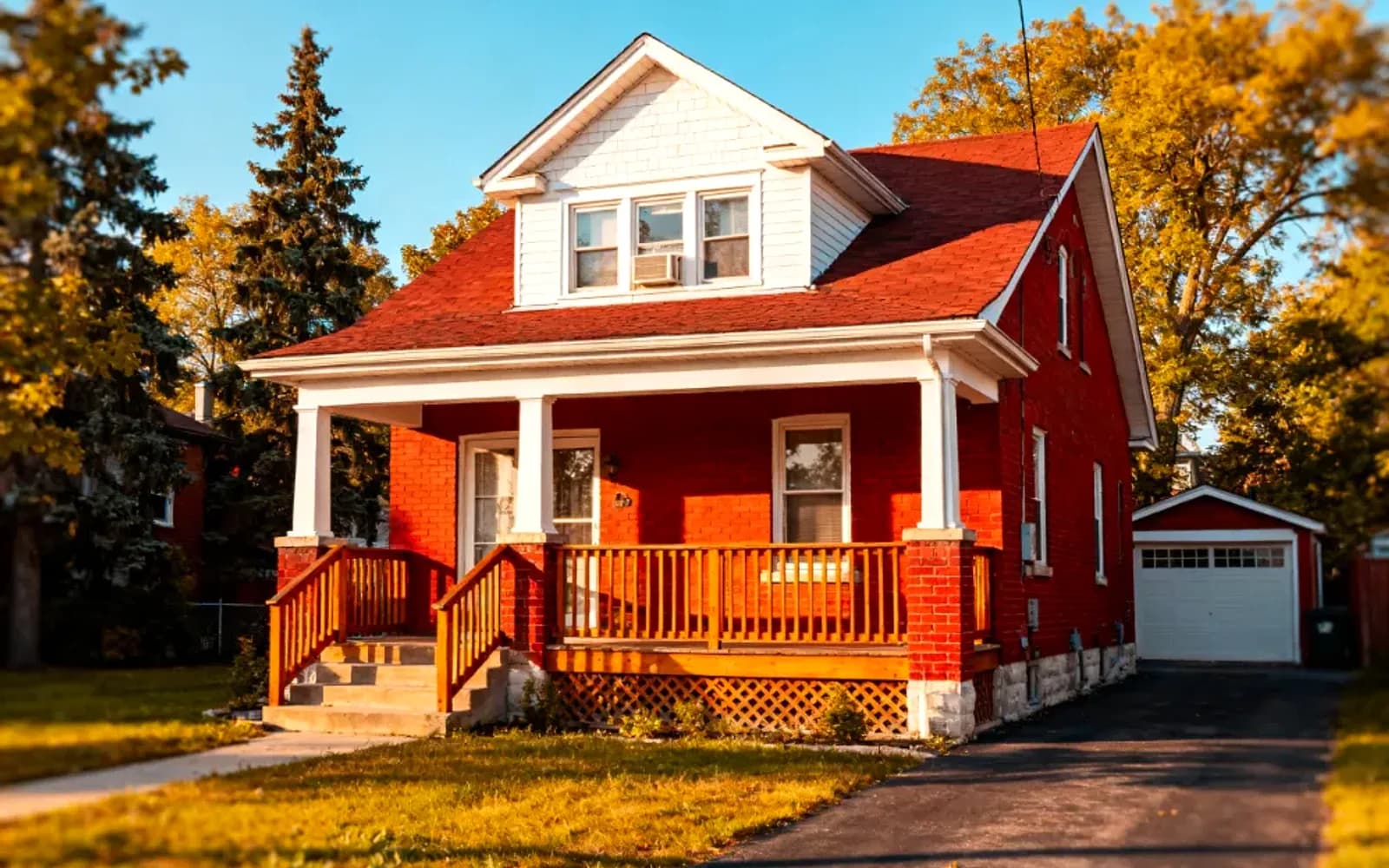Red-brick home with a red roof and covered porch at golden hour in Vaughan, Ontario