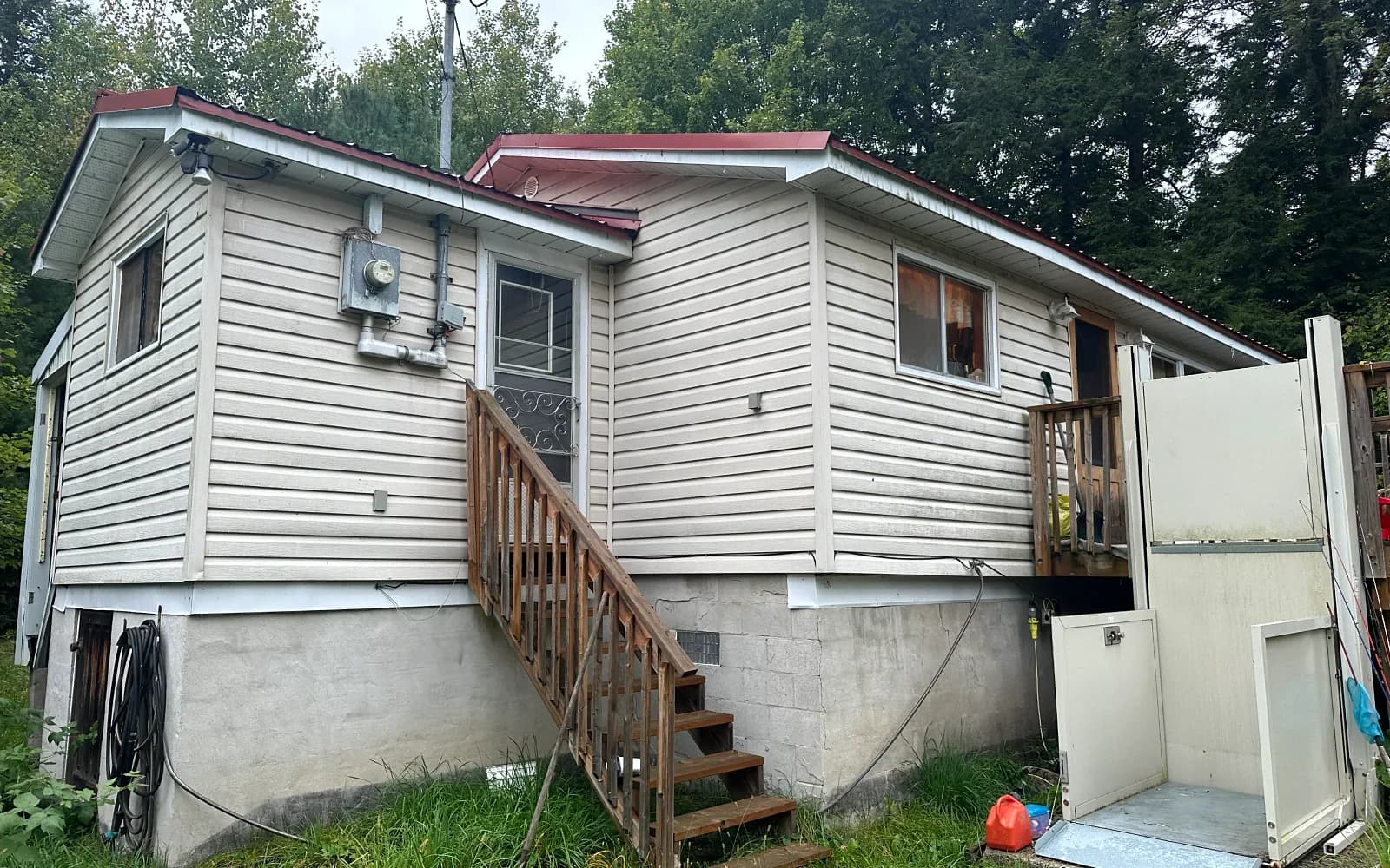 Grey-sided raised bungalow with a deck on a wooded lot in Woodstock, Ontario